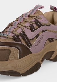 Baskets épaisses beige, marron et rose avec tissu en mesh, lacets rayés, languettes roses réfléchissantes et "Steve Madden" imprimé sur le côté.
