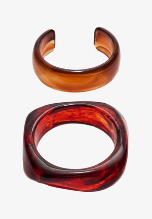 Due due bracciali in resina: uno ambra, rotondo e liscio; uno rosso, quadrato con bordi morbidi, caratterizzato da una texture marmorizzata.