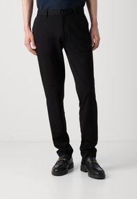 Czarne spodnie na miarę o gładkiej fakturze, charakteryzujące się eleganckim krojem, szlufkami na pasek oraz subtelnym przednim zakładaniem, nadającym wyrafinowany wygląd.