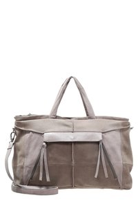 Grand sac de voyage taupe et beige en suede et cuir avec des poignées doubles, des poches zippées à l'avant avec des glands, et une bandoulière amovible.