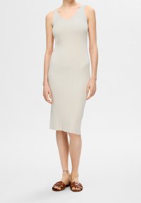 Robe midi gris clair côtelée avec un décolleté en V et de fines bretelles, associée à des sandales marron à enfiler avec un motif tressé.