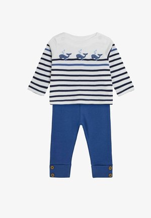 Ribaga pikkade varrukatega topp valge ja tumesinise triibuga, millel on vaalade disain, kombineeritud ühtlaste siniste pükste ja nööpidega allservades.