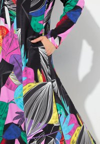 Farbenfrohes Kleid mit schwarzem Grund, das große, abstrakte Blumenmuster in Pink, Grün, Blau und Gelb zeigt. Enthält Seitentaschen.