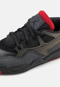 Scarpa da ginnastica nera e grigia con tomaia in suede, dettagli in mesh, accenti rossi e lacci neri. Suola curvata per comfort e supporto.