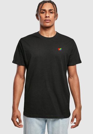 Svart kortärmad t-shirt i bomull med rund halsringning. Har en liten, flerfärgad hjärtgrafik på vänster bröst.