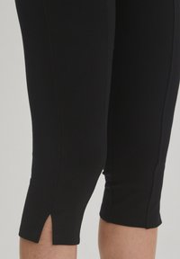 Zwarte leggings met een aansluitend ontwerp, voorzien van zijsplitten aan de zoom en een soepele, rekbare stof voor comfort en flexibiliteit.