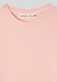 Jasnoróżowa bawełniana koszulka z okrągłym dekoltem. Posiada prostą, gładką fakturę; metka wskazuje rozmiar 4/5 i wysokość 104/110.