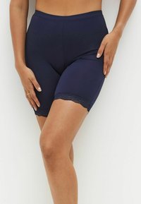 Marineblauwe stretchshorts met een gladde textuur, voorzien van een decoratieve kantafwerking aan de rand. Het getailleerde ontwerp benadrukt de benen.