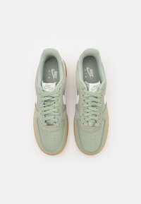 Világossárga edzőcipők texturált velúrból és hálós felsőrészből, fehér részletekkel, perforált díszítéssel és gumitalppal. Nike logó a nyelvén.