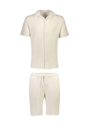 Camicetta a maniche corte color crema con bottoni abbinata a pantaloncini con coulisse dello stesso colore, entrambi realizzati in tessuto morbido e strutturato.