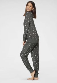 Gray pajama set featuring a star pattern, made from soft material. The top has long sleeves and ribbed cuffs, while the pants are tapered with matching cuffs.