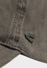 Szara czapka z kordurowej tkaniny z teksturowaną powierzchnią, detalami szycia oraz małym czarnym logo po boku.