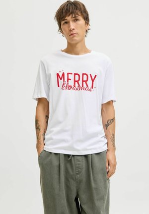 Witte katoenen t-shirt met opvallende rode tekst "MERRY Christmas". Korte mouwen, ronde hals, gedragen met losse lichtgroene broeken.