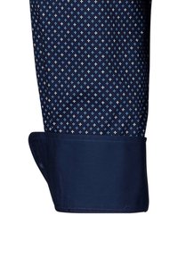 Marineblauer Hemdsaum mit einem kleinen weißen und blauen Kreuzmuster. Glattes, strukturiertes Material mit tailliertem Finish und scharfer Saumabschneidung.