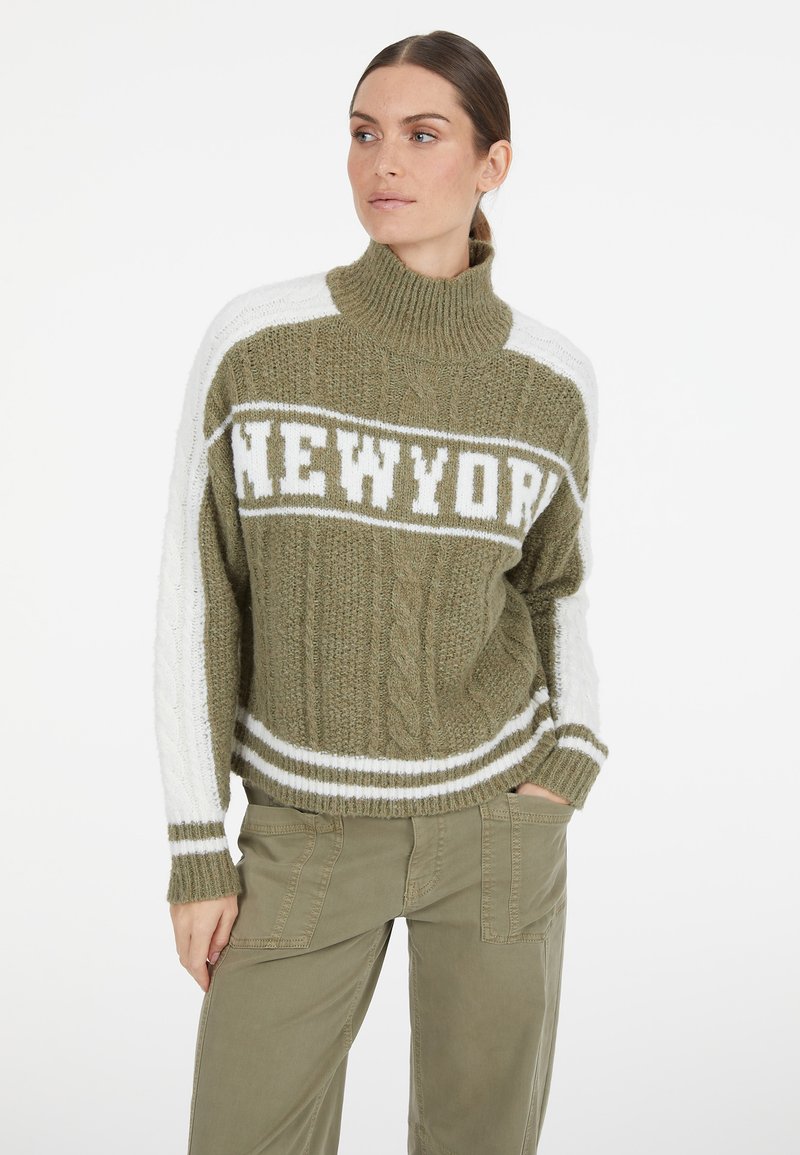 Olivgrüner, gestrickter Pullover mit hohem Kragen, der ein weißes "NEWYORK"-Grafikdesign, weiße Streifen und eine Zopfstricktextur an den Ärmeln aufweist.