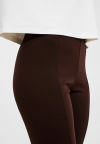 Ruske leggingse, vyrobené z elastického materiálu, navrhnuté s hladkou textúrou a priliehavým strihom, kombinované s bielym prúžkovaným topom.