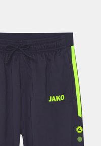 Marinefarbene Sportshorts mit elastischem Bund und Kordelzug. Features in leuchtendem Grün an der Seite und das Logo "JAKO" am linken Oberschenkel. Glatte Textur.