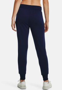 Marineblaue Jogginghosen mit elastischem Bund, gerippten Säumen und glatter Stofftextur. Besitzen ein figurbetontes Design und dezente Stichdetails.