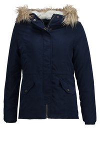 Navy blue women's winter jacket with front zipper, snap-button flap pockets, and hood lined with white faux fur trim.