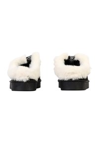 Chaussures noires avec une semelle en caoutchouc épaisse, dotées d'un bord en fausse fourrure blanche à l'arrière et d'un tissu noir texturé sur la partie supérieure.
