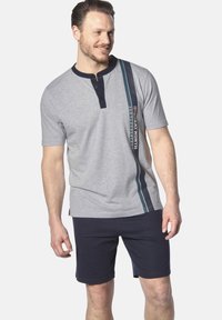 Gray short-sleeve polo shirt with a navy collar and buttons. Features a vertical blue and white stripe with text detail. Paired with navy shorts.