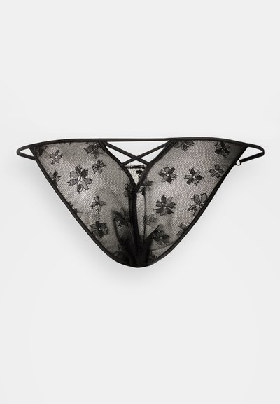 Tanga de renda preta com padrões florais e tecido em tule transparente. Alças ajustáveis criam um desenho em cruz nas costas.