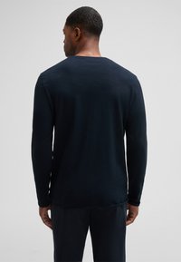 Langärmliges, dunkelblaues Hemd aus weichem Stoff. Verfügt über eine lockere Passform und ein geripptes Muster am Hals und an den Manschetten. Einfaches, minimalistisches Design.