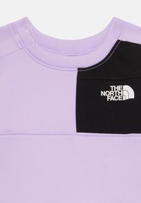 Ljuslila sweatshirt med en svart bröstpanel och vit logga. Texturerat tyg med synliga söm detaljer. Klassisk crewneck-design.