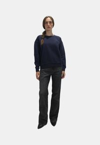 Felpa blu navy con scollatura rotonda e polsini a coste, abbinata a un paio di jeans larghi grigio scuro. Texture lisce con dettagli minimi.