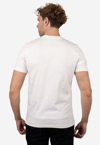 Camiseta de manga corta para hombre en algodón color blanco roto. Presenta cuello redondo, silueta ajustada y textura suave. Sin logotipos ni patrones visibles.