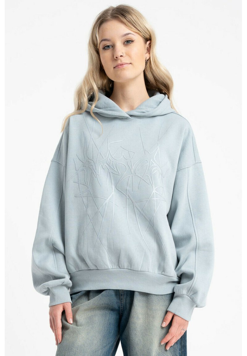 Jasnoniebieska, oversize bluza z kapturem wykonana z miękkiego materiału, z teksturowanym, abstrakcyjnym wzorem oraz sznurkiem przy kapturze. Długie, szerokie rękawy oraz prążkowany dół.