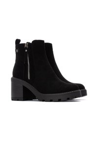 Botas de tobillo de ante negro con tacón grueso, cremallera lateral y suela texturizada. Cuentan con una lengüeta en la parte posterior para facilitar su calzado.
