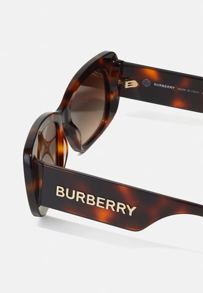 Burberry saulesbrilles ar bruņurupuču raksta rāmi, brūnām lēcām un izteiksmīgu zelta logotipu sānos. Leņķveida dizains ar spilgtu apdari.