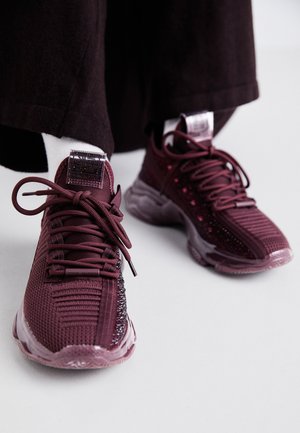 Scarpe da ginnastica color bordeaux con tomaia in rete, dettagli testurizzati, lacci tondi e suola in gomma trasparente; presenta un logo sulla linguetta e sul tallone.