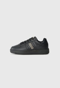Baskets en cuir noir avec une finition texturée, dotées d'un détail de logo doré sur le côté et d'une semelle en caoutchouc conçue pour l'adhérence.