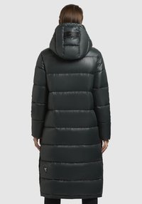 Dlhý puffer kabát v tmavozelenej farbe, so kapucňou, prešívanou textúrou a detailom loga na chrbte, s hladkým, lesklým povrchom.