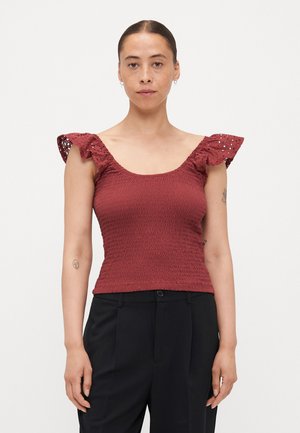 Red smocked top with wide, cut-out lace sleeves. Fitted design, textured fabric, and a scoop neckline. Paired with black trousers.