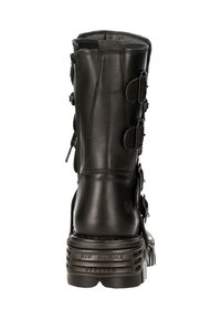 Bottine noire en cuir hauteur genou avec plusieurs boucles, bout rond et une semelle chunky texturée. Caractéristiques d'une finition lisse et d'une construction robuste.