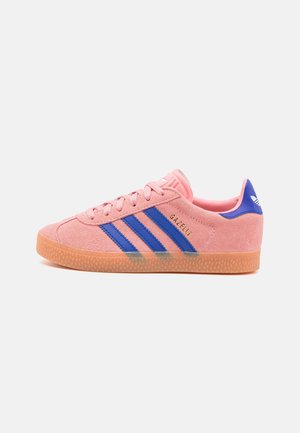 Rosa Wildleder Adidas Gazelle Sneaker mit blauen Streifen, Gummisohle und gebrandeter Fersenlasche, von der Innenseite auf hellem Hintergrund gezeigt.