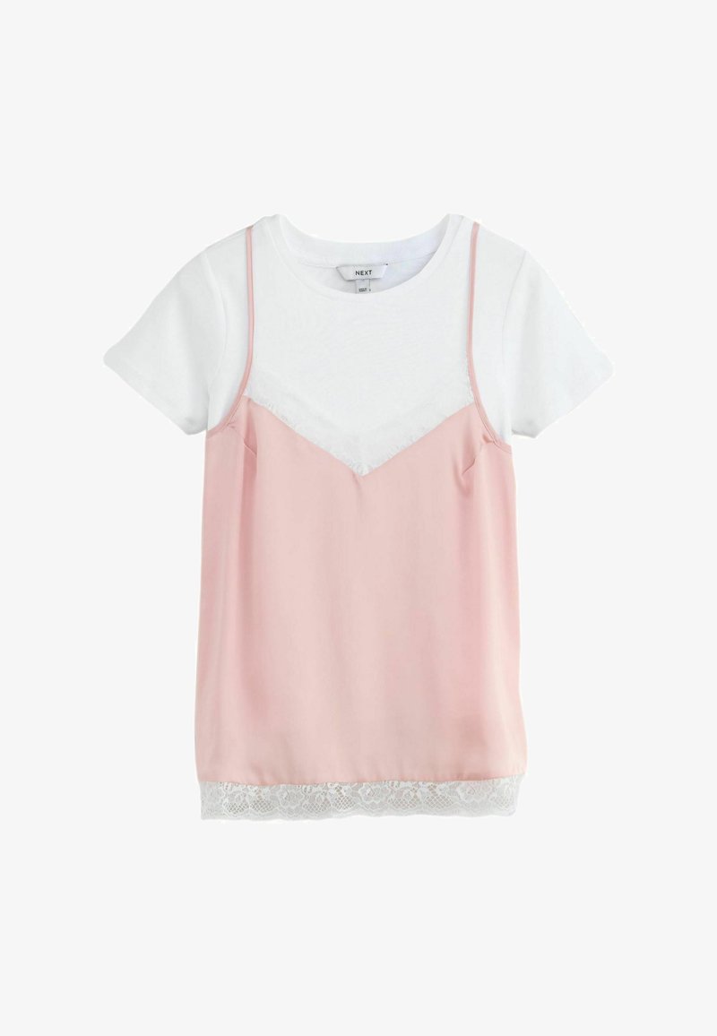 T-shirt blanc à manches courtes sous un caraco rose clair à fines bretelles et bordure en dentelle blanche à l'ourlet.