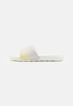 Sandal en slide blanche avec une sangle pastel irisée et une semelle rembourrée, présentée en profil sur un fond blanc uni.