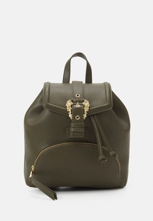 Sac à dos en cuir texturé vert foncé avec poche avant zippée, fermeture à rabat et boucle dorée décorative sur fond gris clair.
