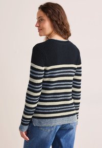 Randig tröja i marinblått, krämfärgat och ljusblått garn. Ribbade strukturer med rundad halsringning och långa ärmar. Har en avslappnad passform.