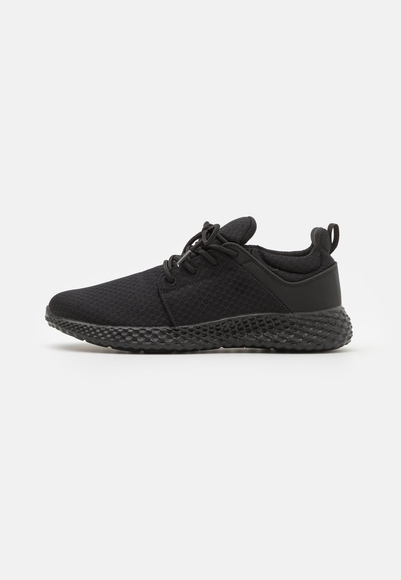 Baskets athlétiques légères noires avec semelle texturée, empeigne en mesh, fermeture à lacets, col rembourré et languette au talon.
