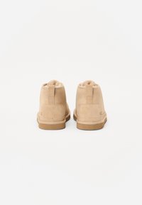 Botas de tobillo de ante color marrón claro con puntera redonda, forro suave de piel, detalle de talón reforzado y suela de goma para tracción.