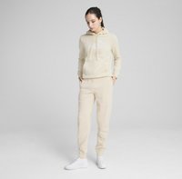 Beige hoodie met een trekkoord en wit "PUMA" logo, gecombineerd met bijpassende taps toelopende trainingsbroeken en witte sneakers. Gladde textuur, ontspannen pasvorm.