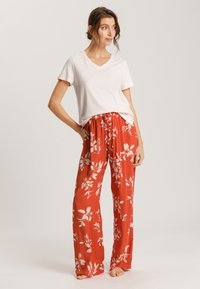 Rode bloemenpatroon broek met een losse pasvorm en een elastische tailleband, gecombineerd met een effen wit T-shirt met V-hals. Zachte stofstructuur.