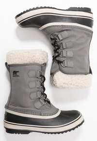 Bottes imperméables grises avec semelles en caoutchouc noir, accents blancs et doublure en fausse fourrure. Présente cinq œillets pour les lacets et une tige en tissu texturé.