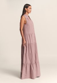 Robe maxi en tissu mauve doux, dotée d'un col avec revers, sans manches, boutonnée à l'avant et à ourlet à volants avec un motif texturé.