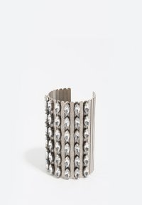 Pulsera metálica con superficie texturizada, con franjas verticales y filas de gemas claras de forma ovalada a lo largo de un lado.